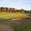 Hole #2 is a dogleg left with trees and houses left and mounds and trees right. A bunker to the left front and along the back guards the gre