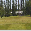 Hole #10 is a short par 4. The driving range fence and trees line the left fairway. There are also trees lining the right side and one bunker to the right front of the green. The green is relatively flat.