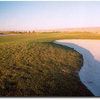 More water in a dry landscape - barely seen to the left, water runs along the approach half of the fairway on the 355-yard, par 4 #15, wrapping right around the back of the green in the distance, which slopes into the water. Bunkers provide the excitement
